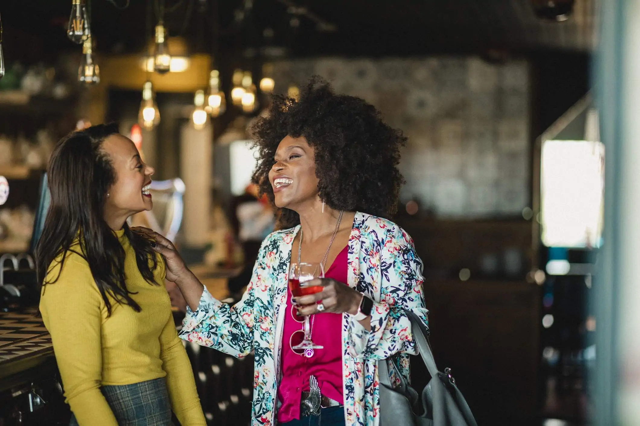 Image depicts two people drinking wine and laughing together.