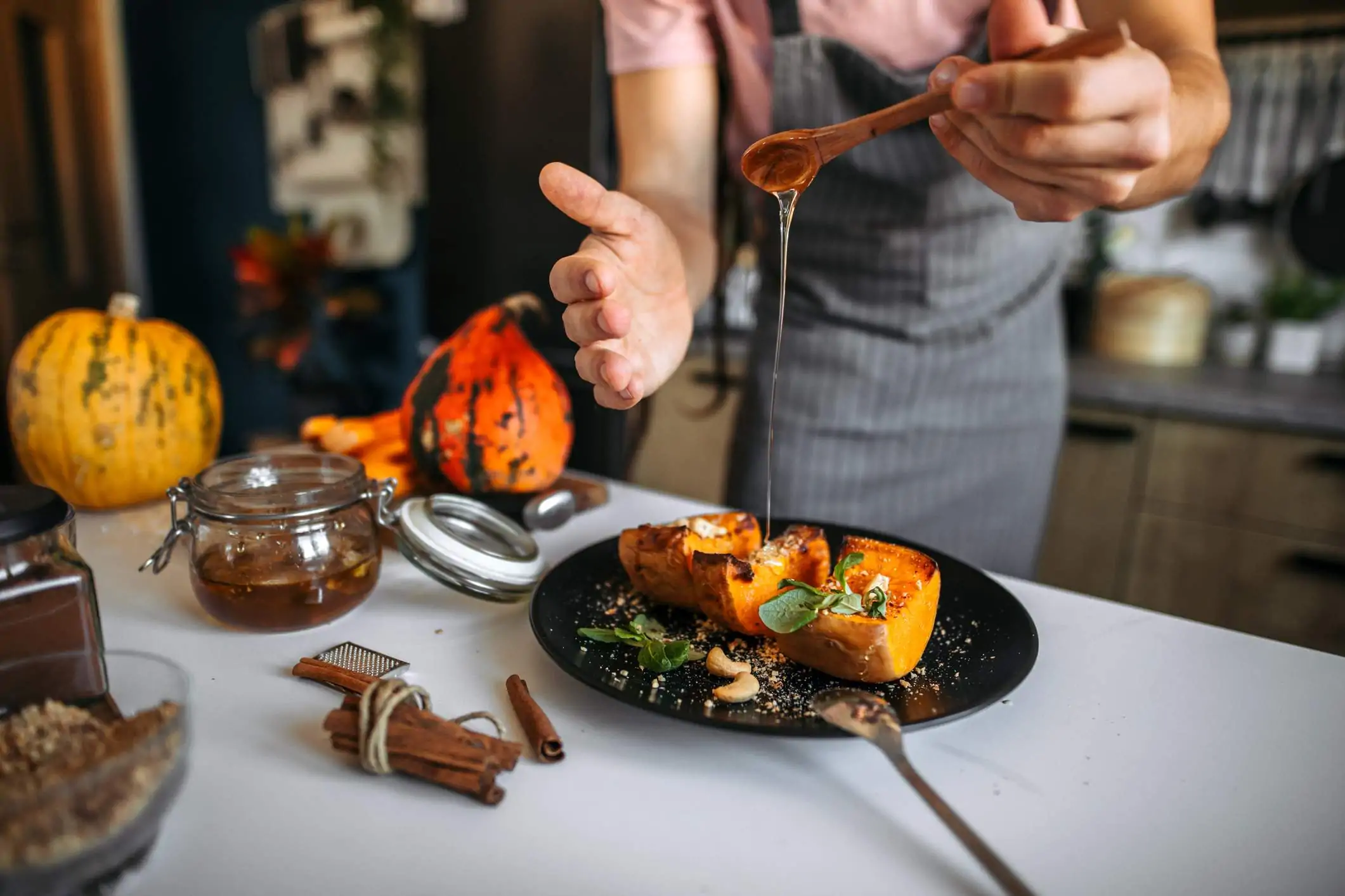 Image depicts a chef pouring honey over a squash.