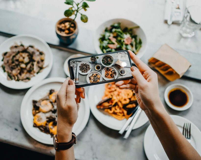 Social media influencer photographs food during a restaurant promotion
