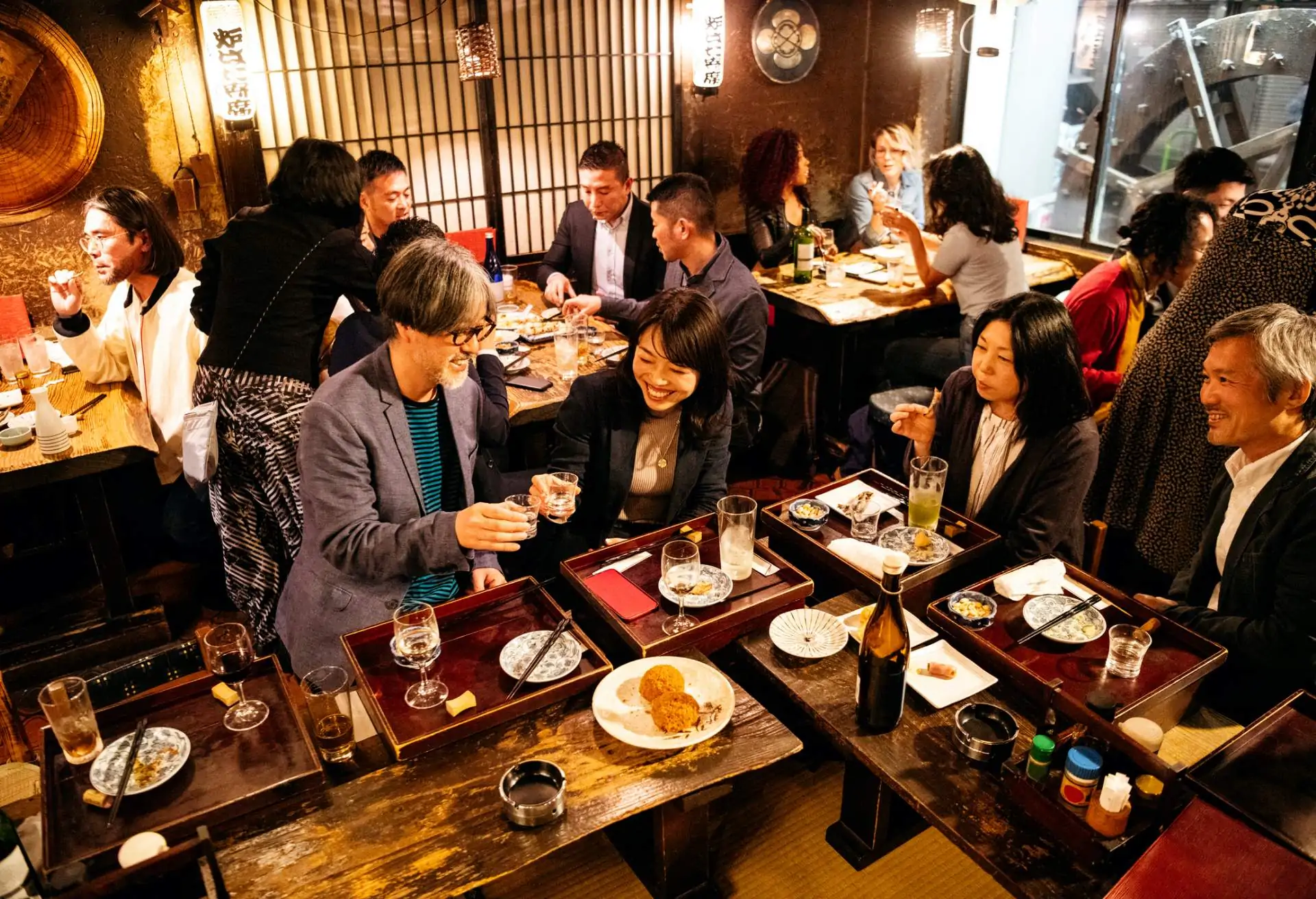 A crowd has fun in the bar and dining room of a busy restaurant