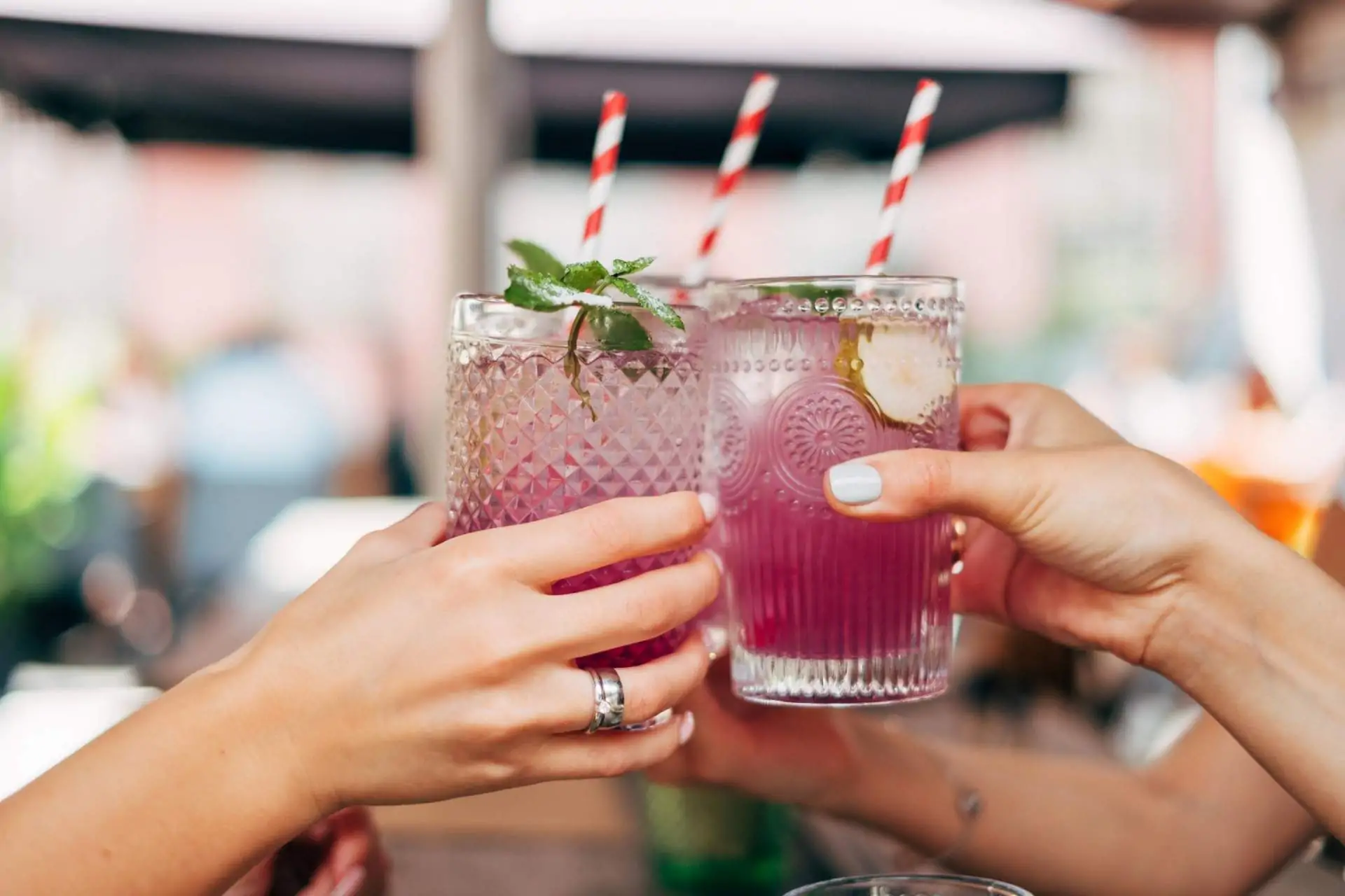 Image depicts two people out of frame cheersing pink, non-alcoholic beverages.