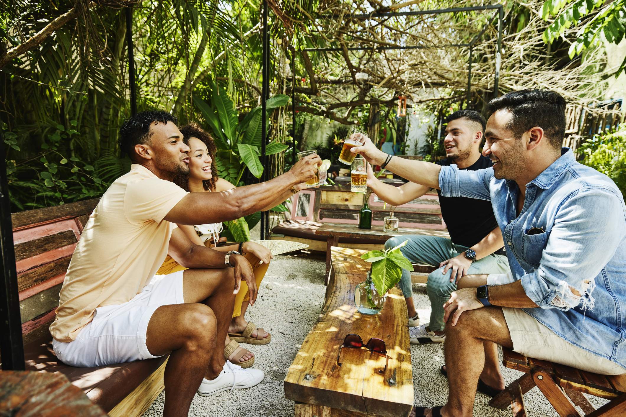 Image depicts a group of people sitting at an outdoor set up at a restaurant, cheersing drinks.