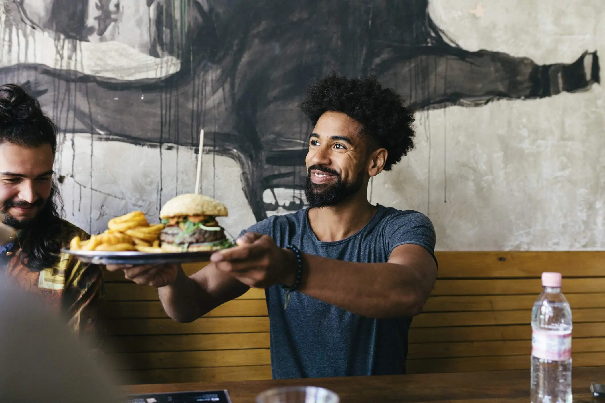 Image depicts a diner receiving a plate of food from a restaurant worker.