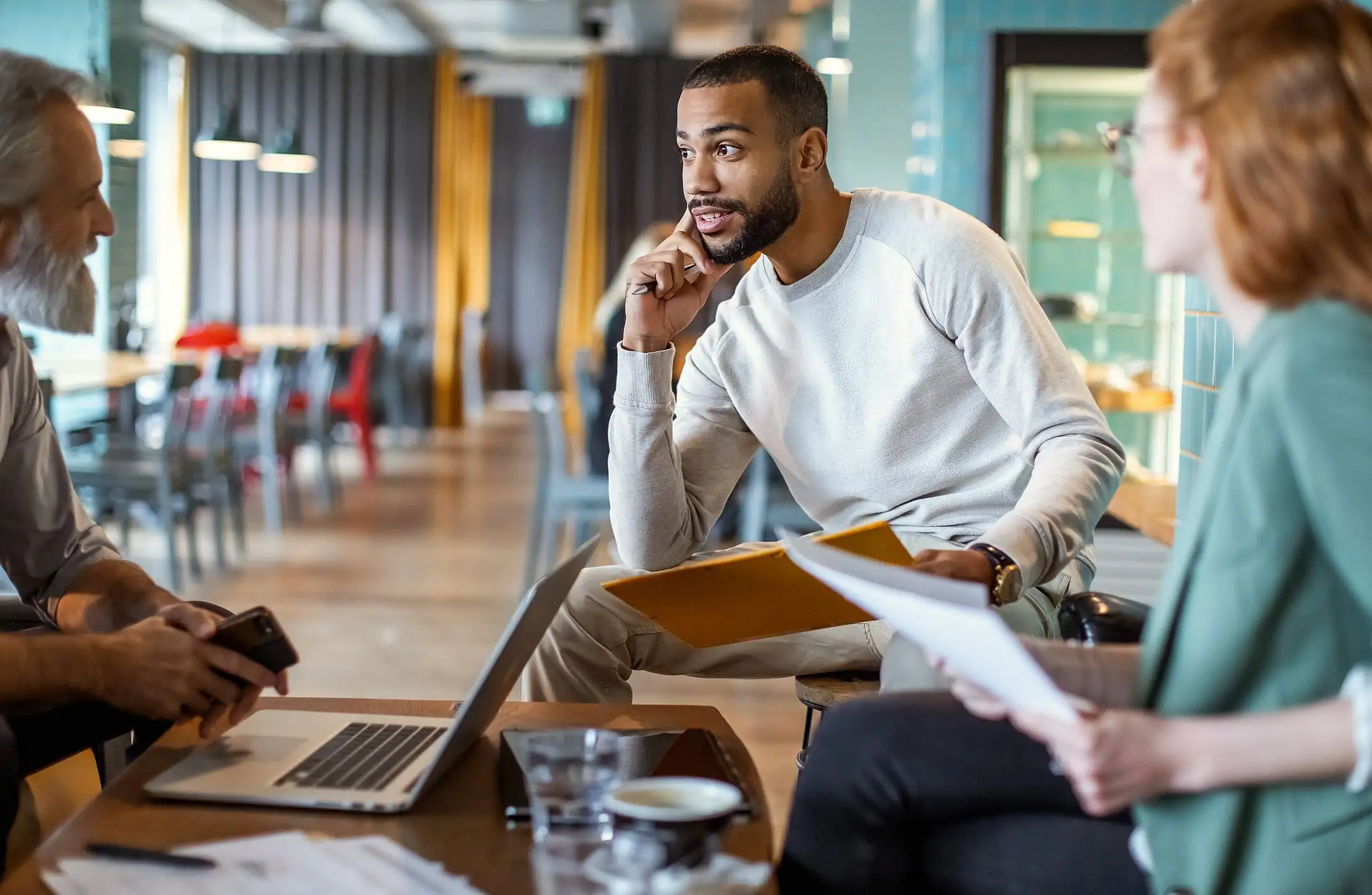 Image depicts three restaurant workers discussing metrics and data at a table.