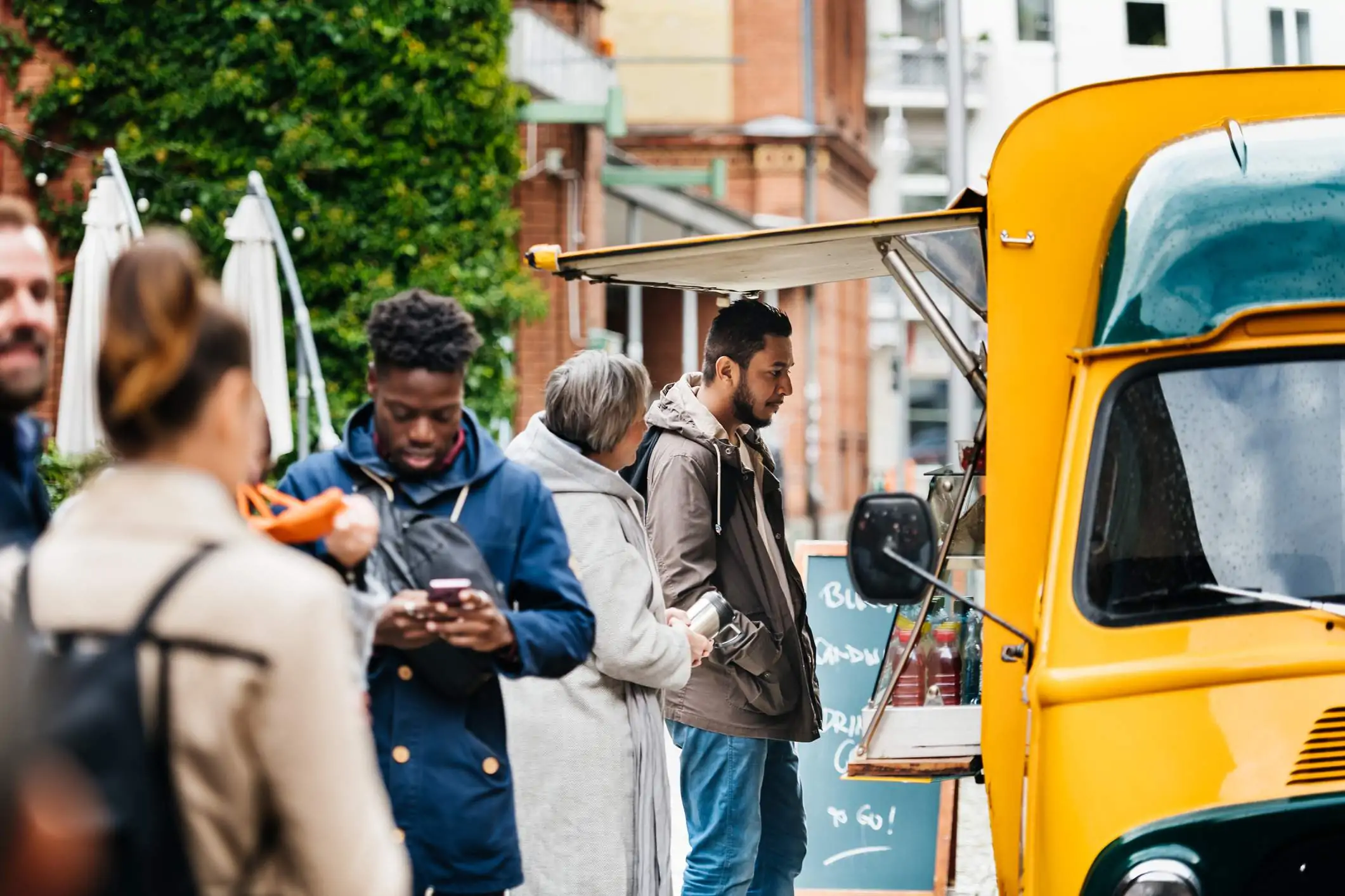 Image depicts a line waiting to order food from a food truck.