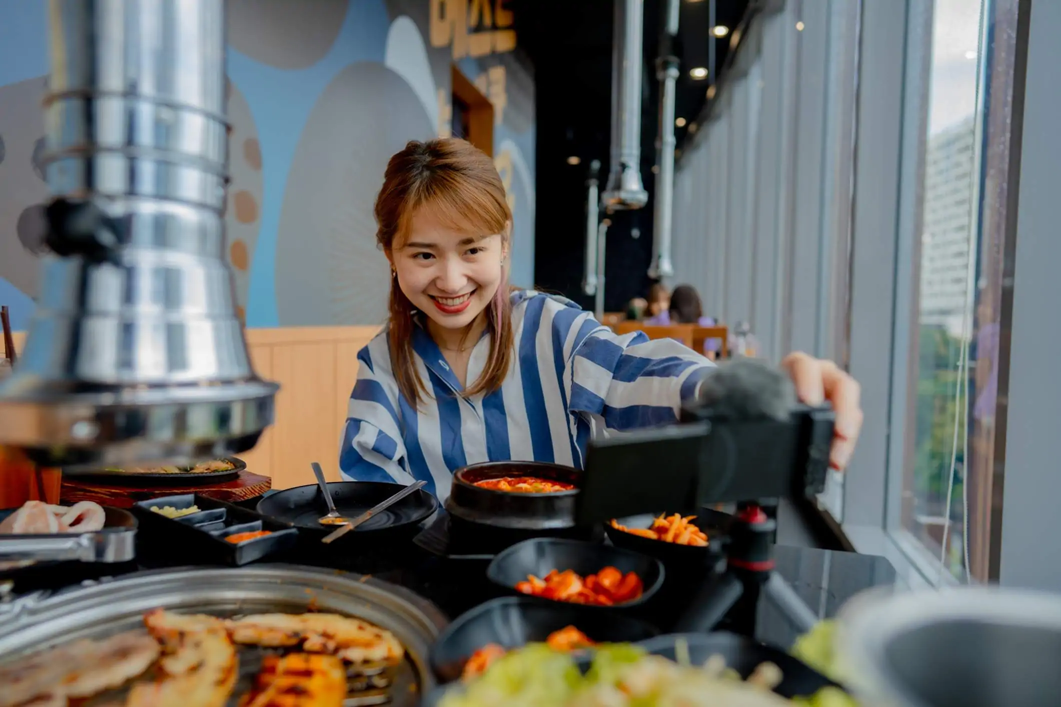 Image depicts a diner at a restaurant vlogging their food experience.