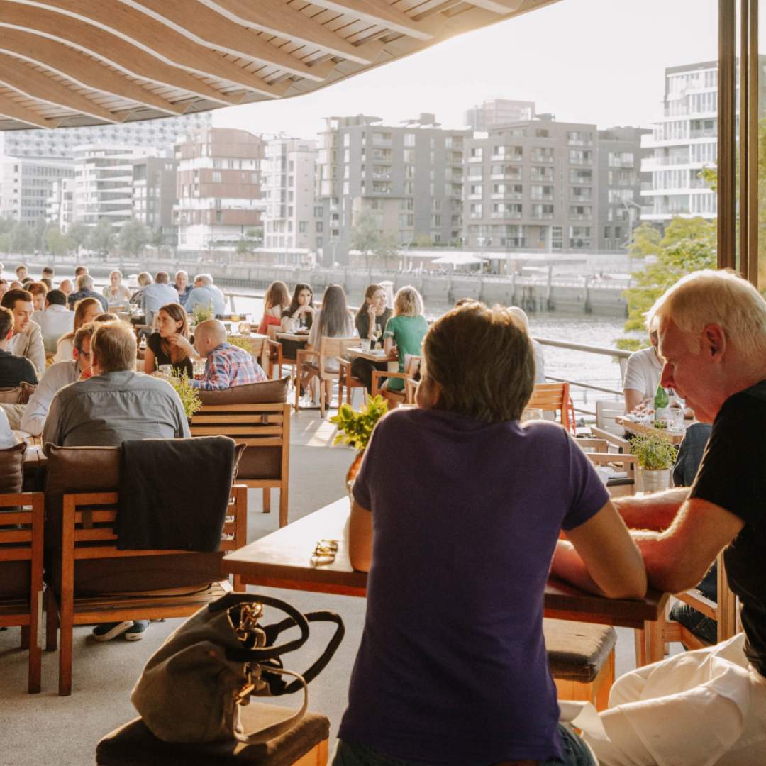 Diners enjoy the view from a restaurant’s outdoor seating area overlooking the water