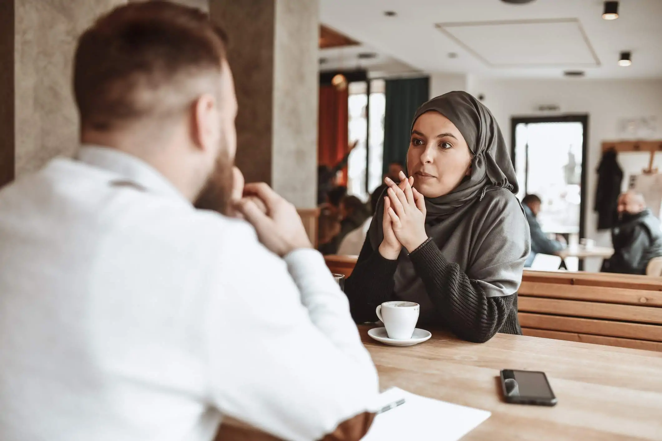 Image depicts two people conducting an interview inside a restaurant.