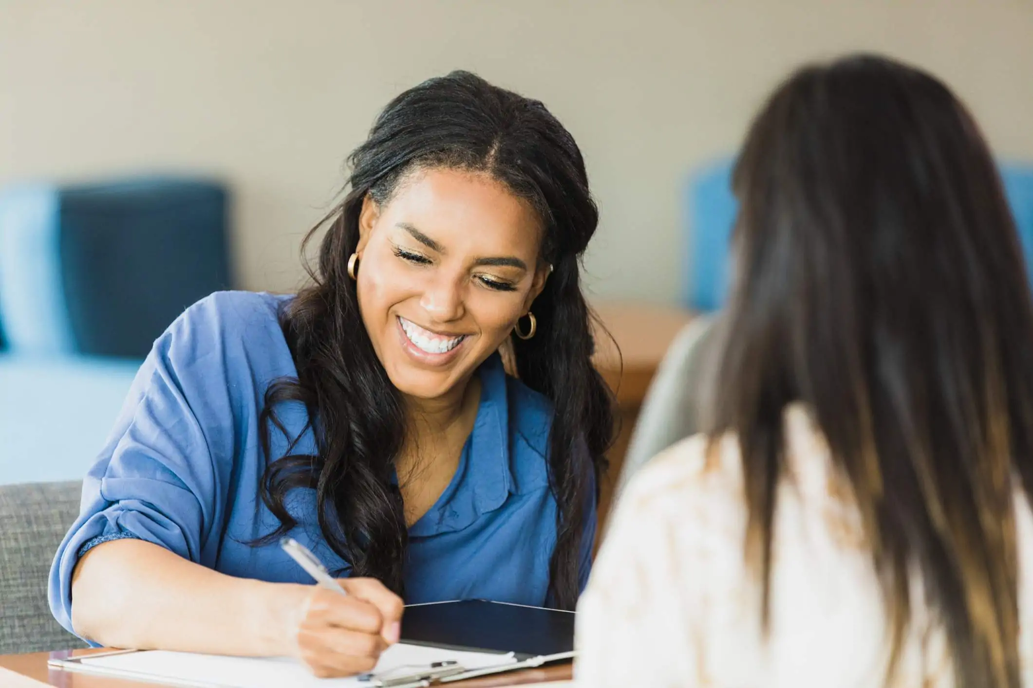 Image depicts a restaurant worker taking notes as they interview a candidate.