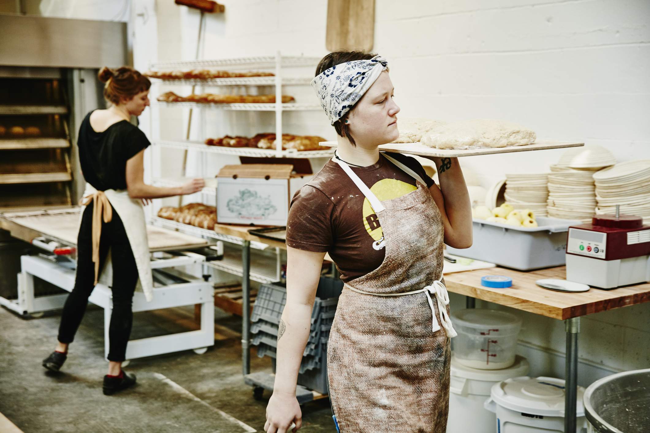 Image depicts two restaurant workers making bread in a back room. 