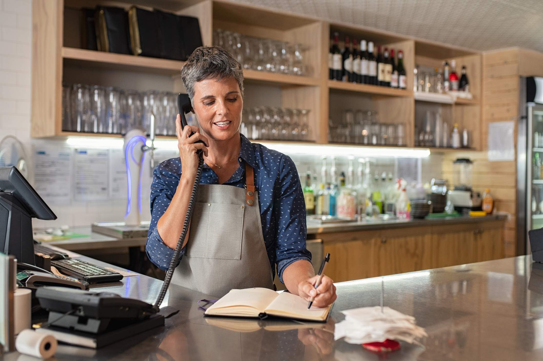 Image depicts a restaurant worker talking on the phone.