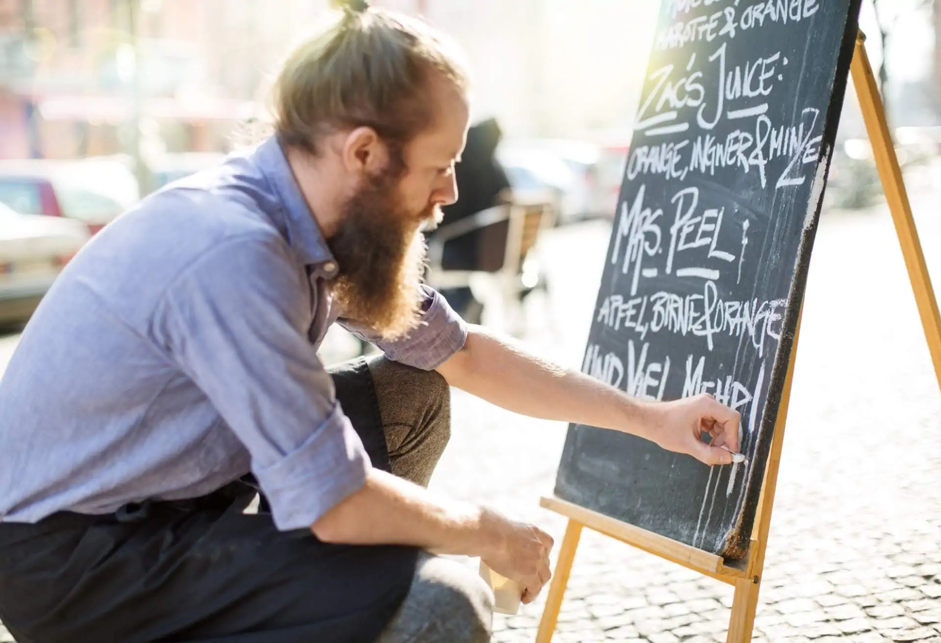 A restaurant employee updates the chalkboard sign on the sidewalk