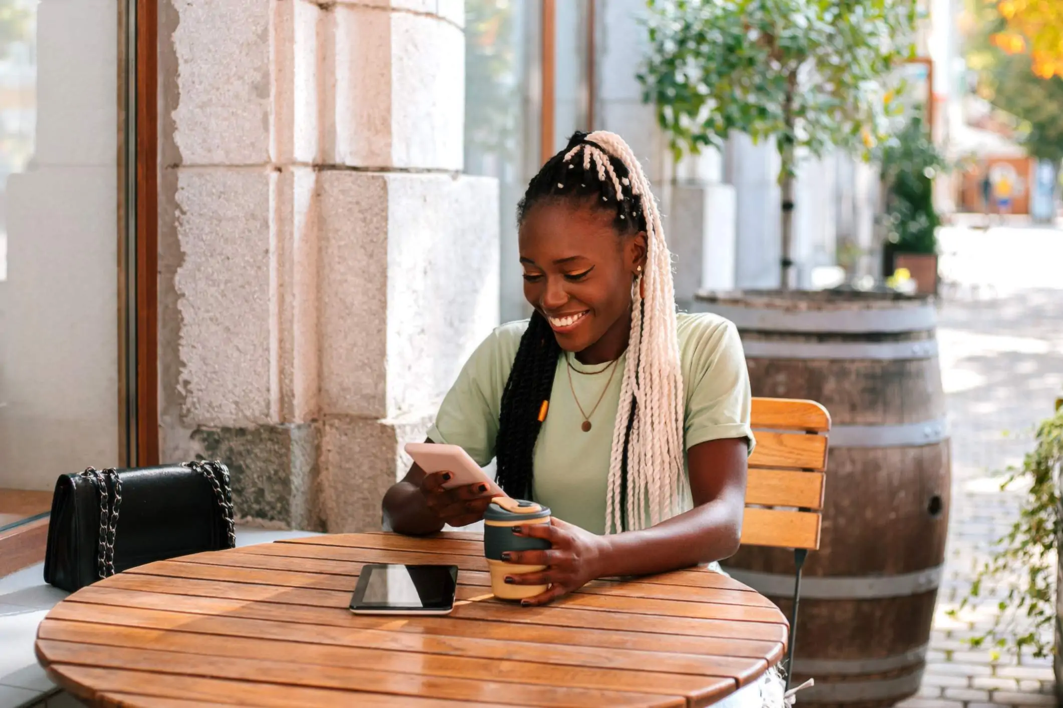 Image depicts a diner sitting at a table outside of a restaurant using a phone.