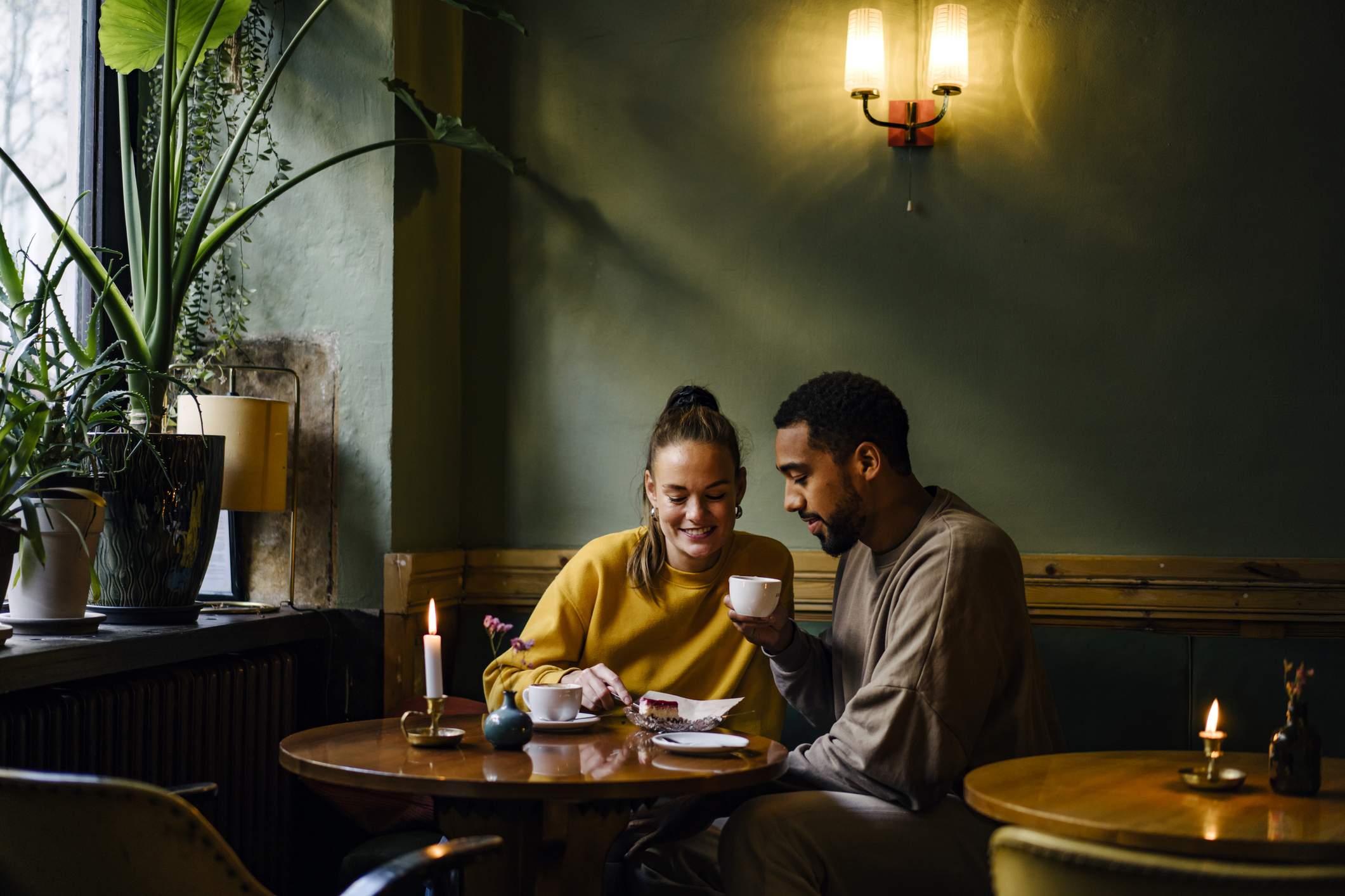 Image depicts two diners sitting at a booth in a restaurant drinking coffee. 
