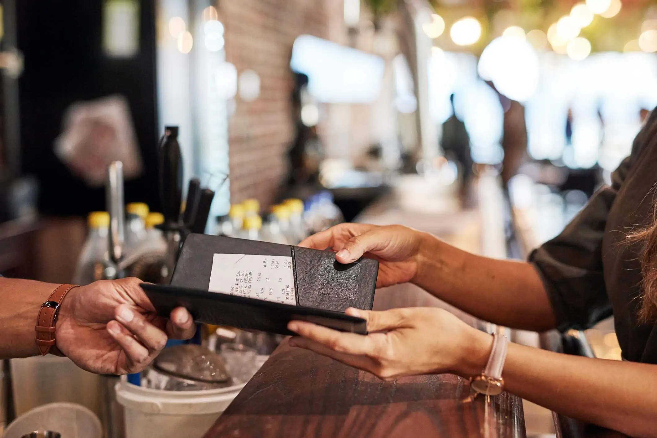 Image depicts two people exchanging a check in a restaurant.