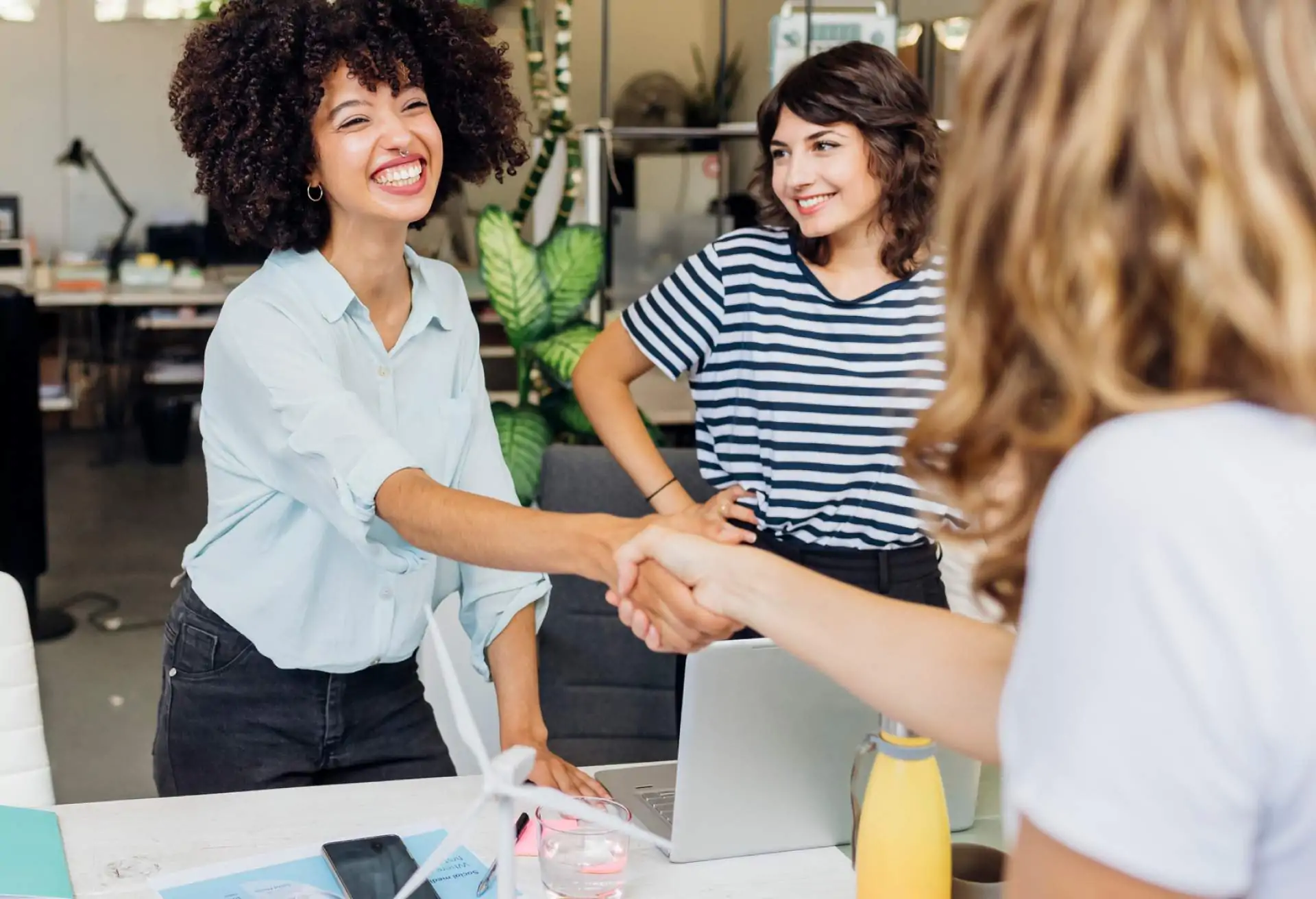 Restaurant employees smile and shake hands during an employee referral