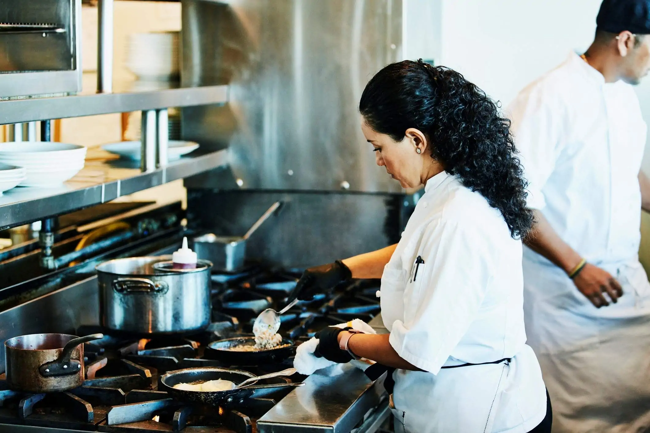 Image depicts a chef preparing food on a gas stove