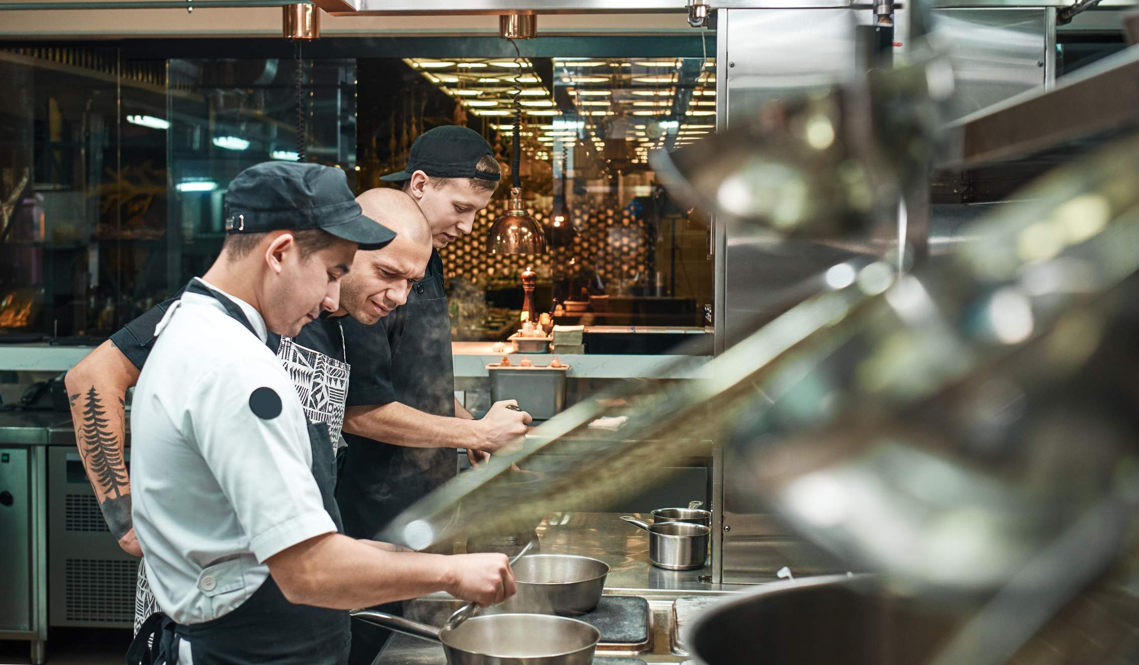 Image depicts three restaurant workers cooking in a kitchen. 