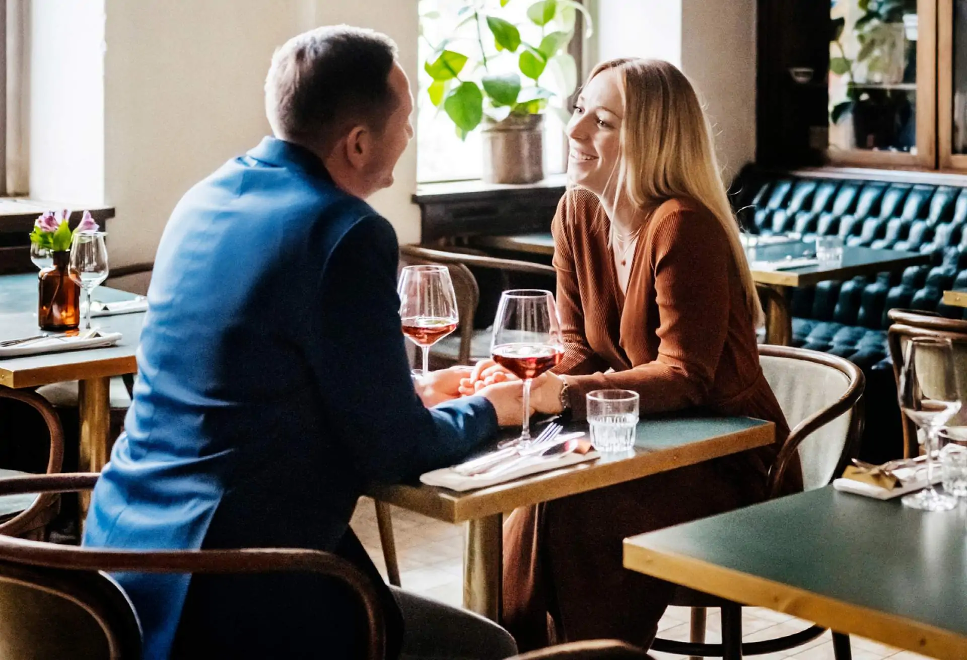 Image depicts two people having a conversation while sitting at a table in a restaurant.