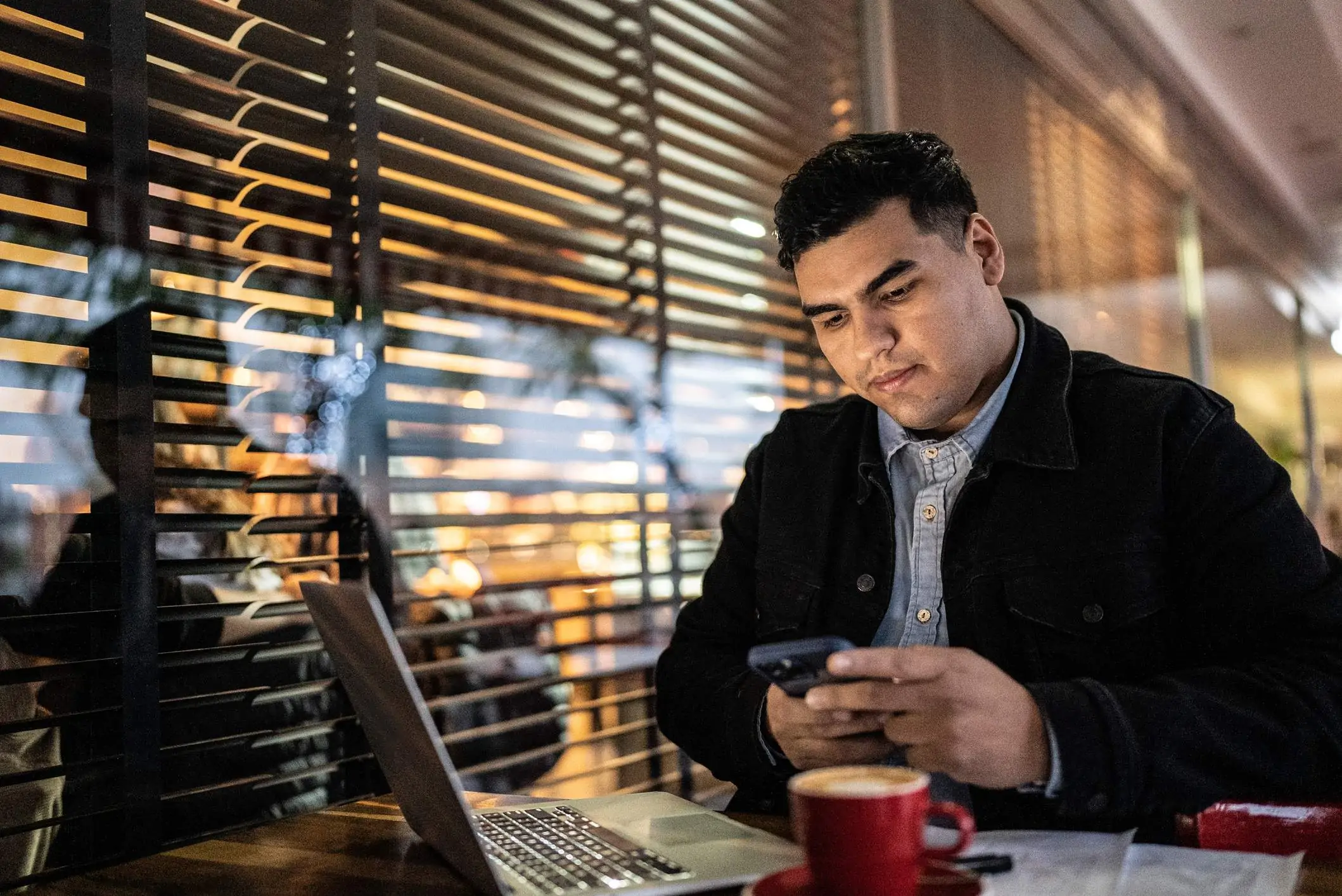 Image depicts a diner sitting at a restaurant table while using their mobile phone.