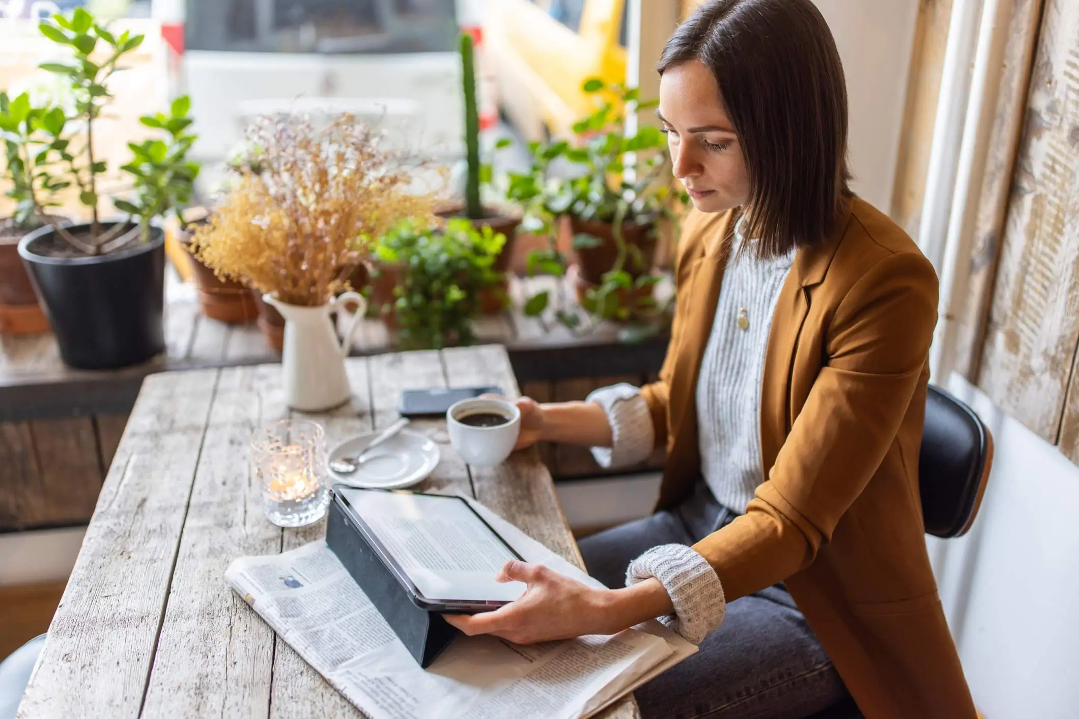 Image depicts a diner eating at a restaurant while checking their email on a mobile device.