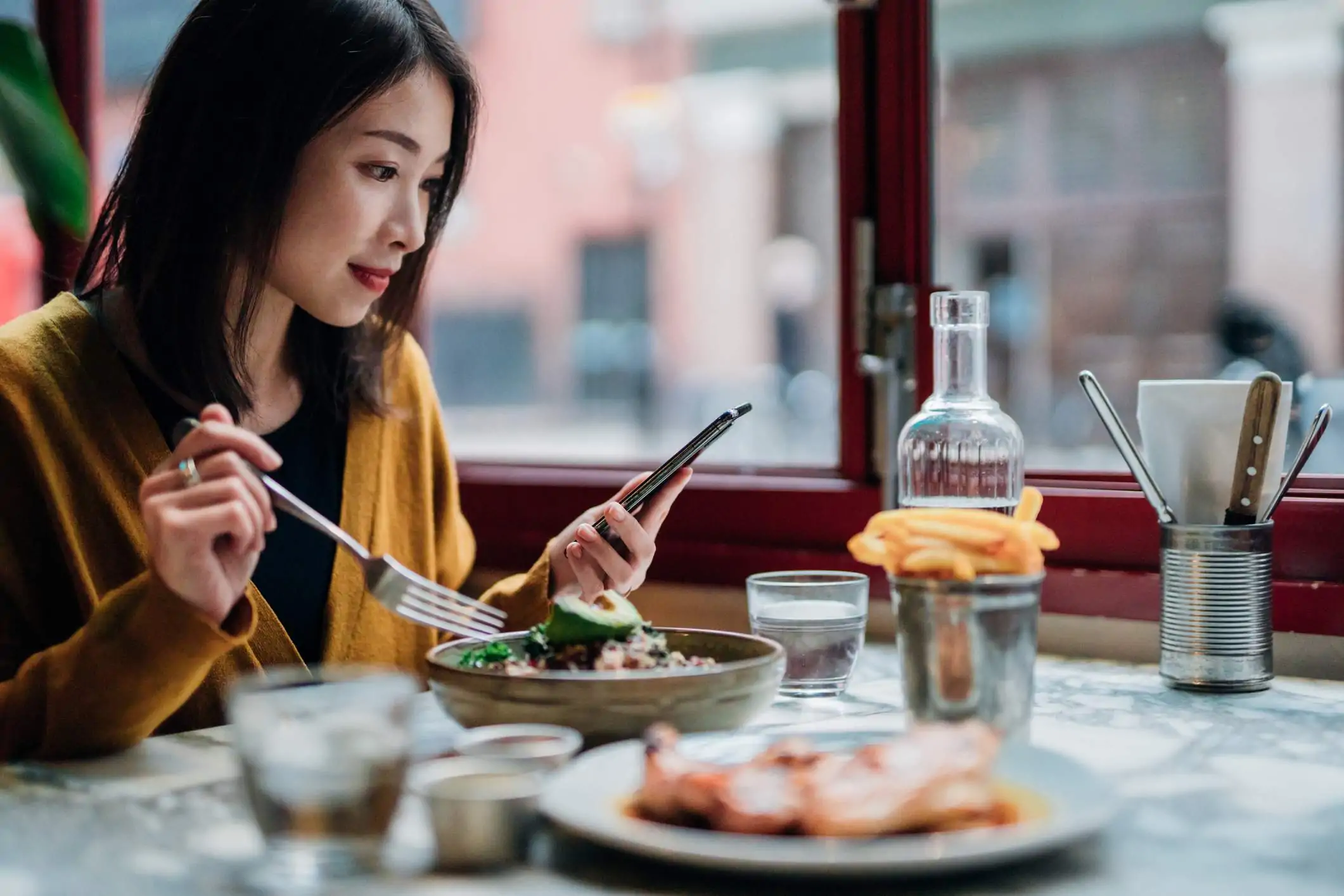 Image depicts a restaurant worker having coffee while using a tablet.