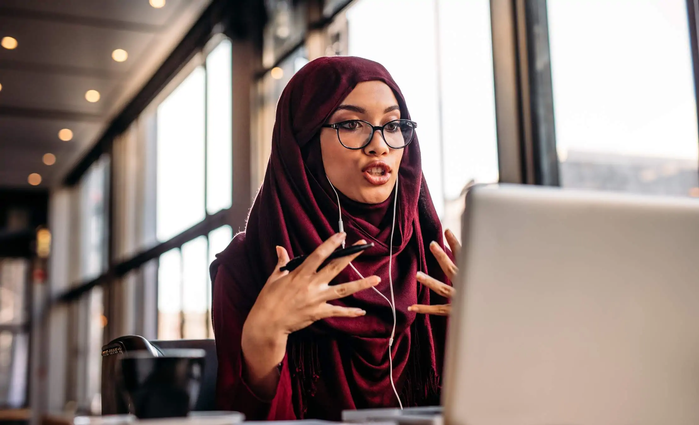 Image depicts a person talking to someone on a computer for an interview.