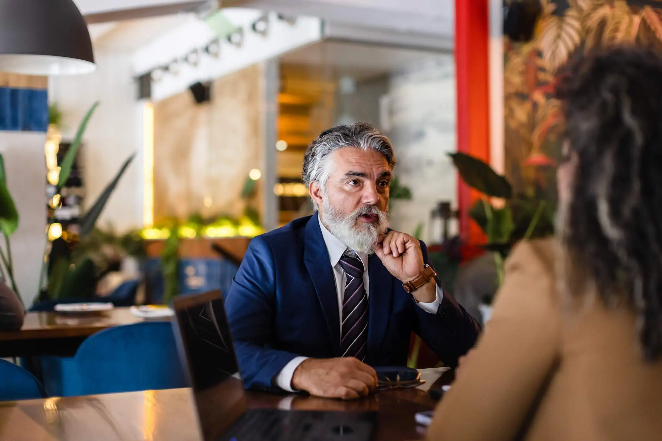 Image depicts a restaurant worker in a suit having a conversation with a colleague.