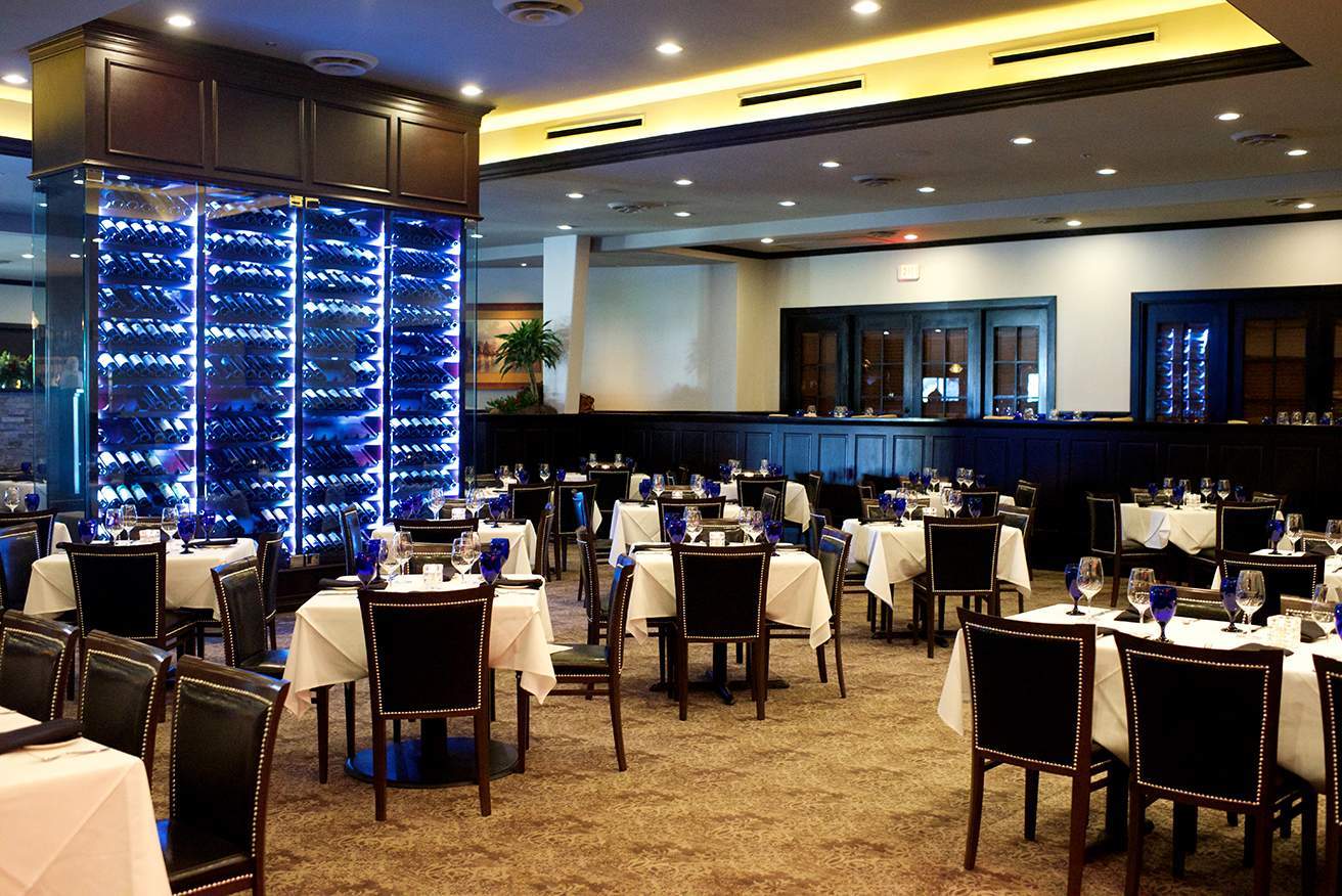 Image depicts the interior of a restaurant with a large wine shelf.