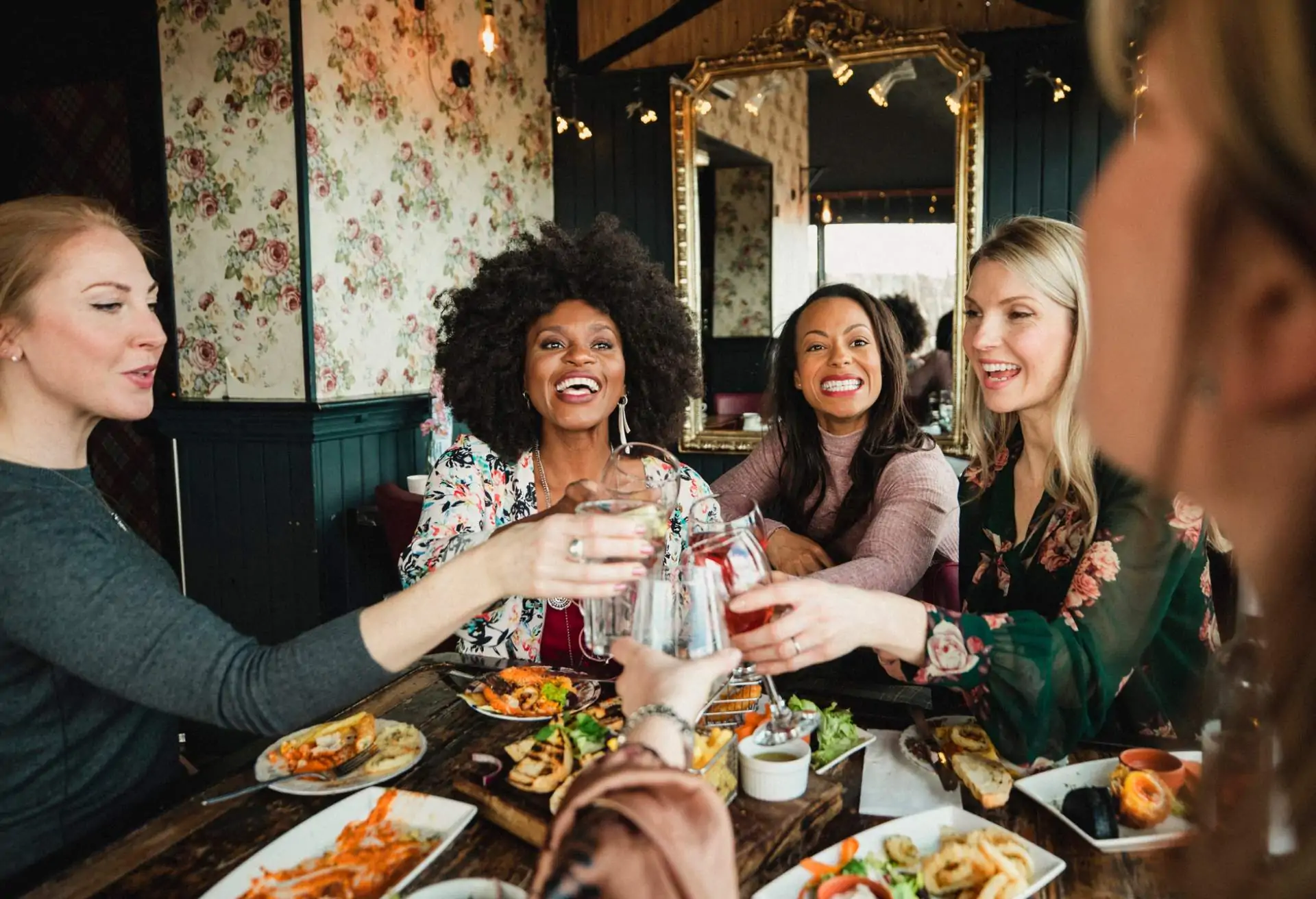 Image depicts a group of diners cheersing at a restaurant.