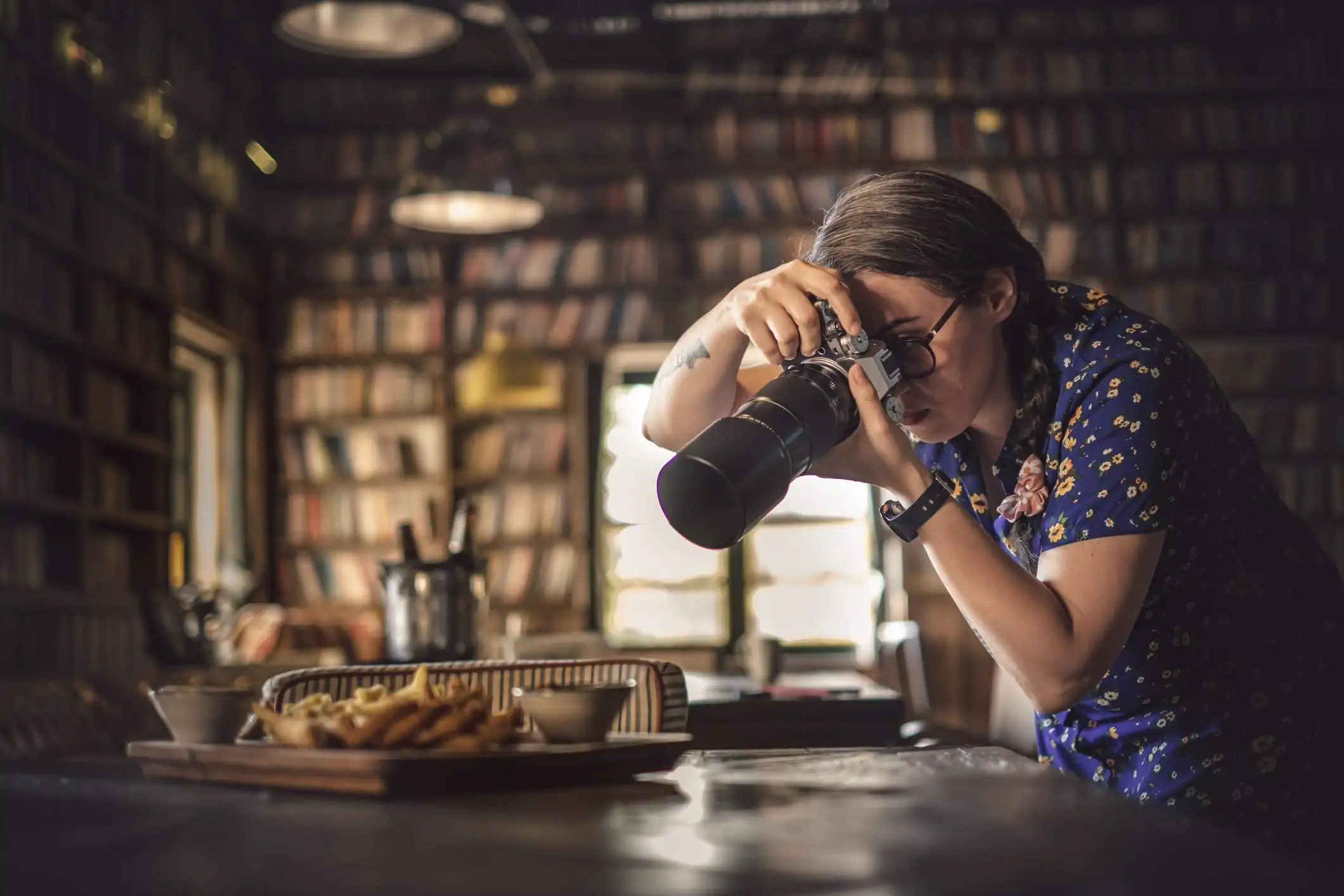 Image depicts a restaurant worker photographing food.