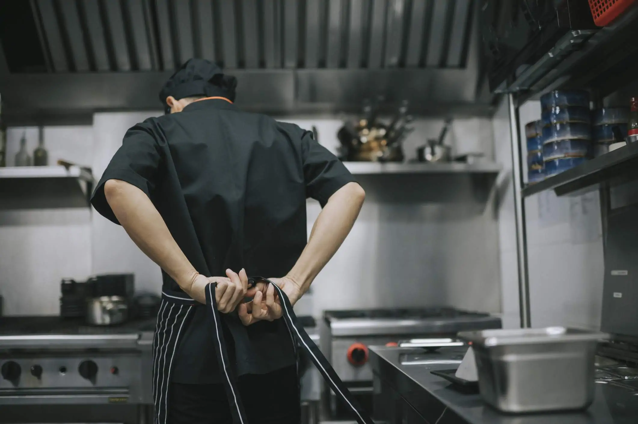 Image depicts a restaurant worker tying an apron behind their back.