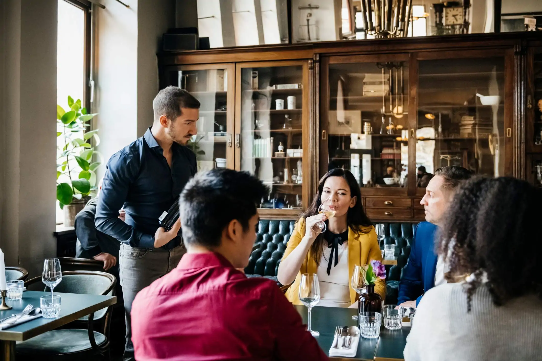 Image depicts a server taking care of a group of people at a table.