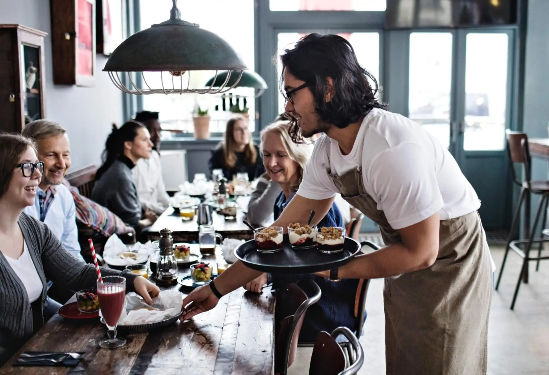 Restaurant service in action: A server brings a table of happy guests their order from the kitchen.