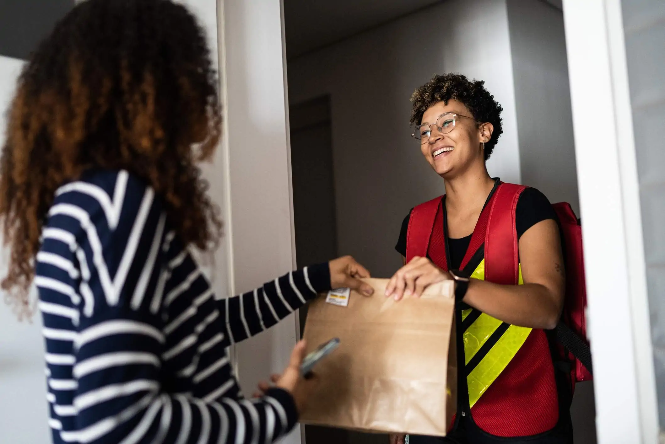 Image depicts a delivery person dropping off food to a diner.