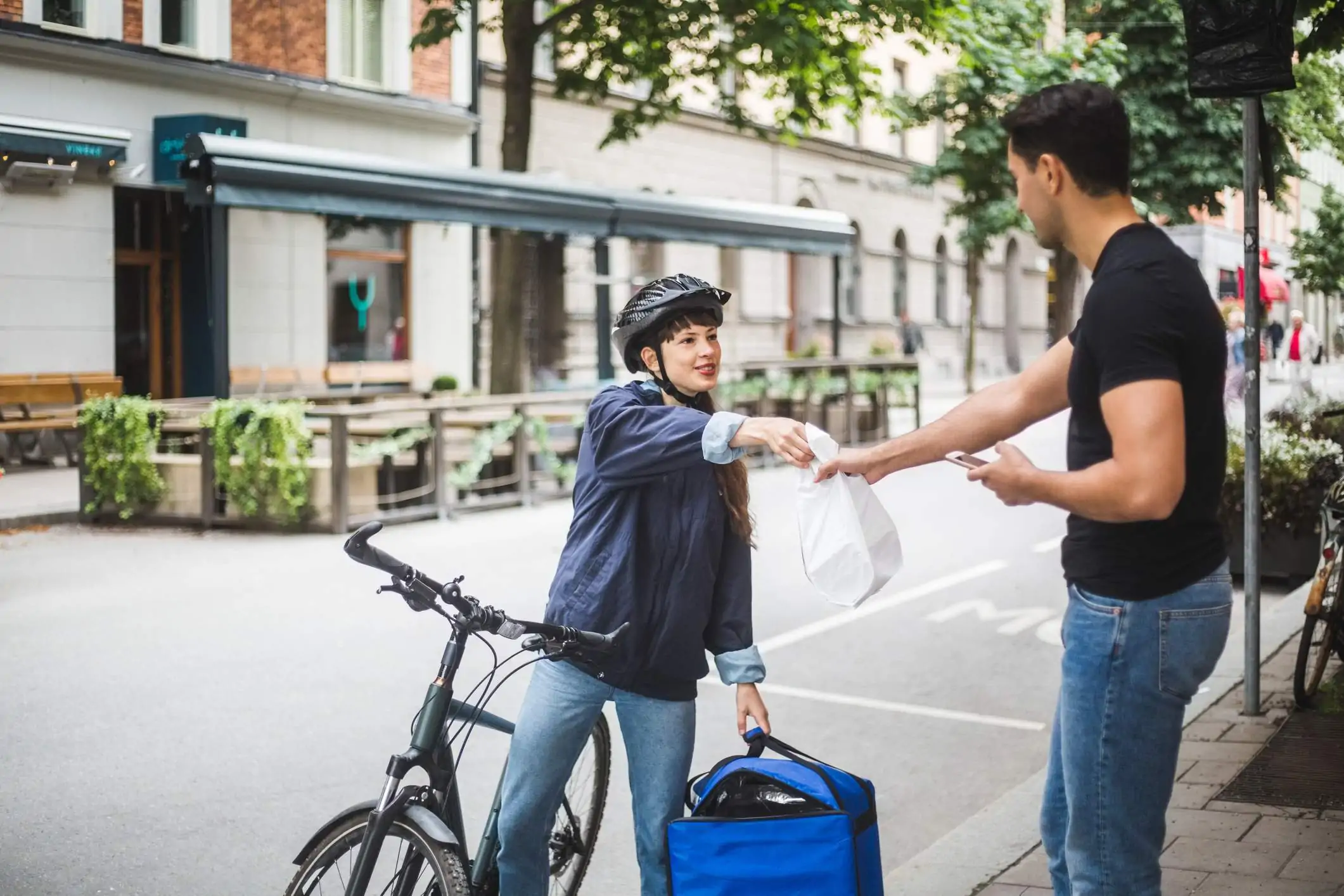 Image depicts a delivery driver handing off food to a customer.