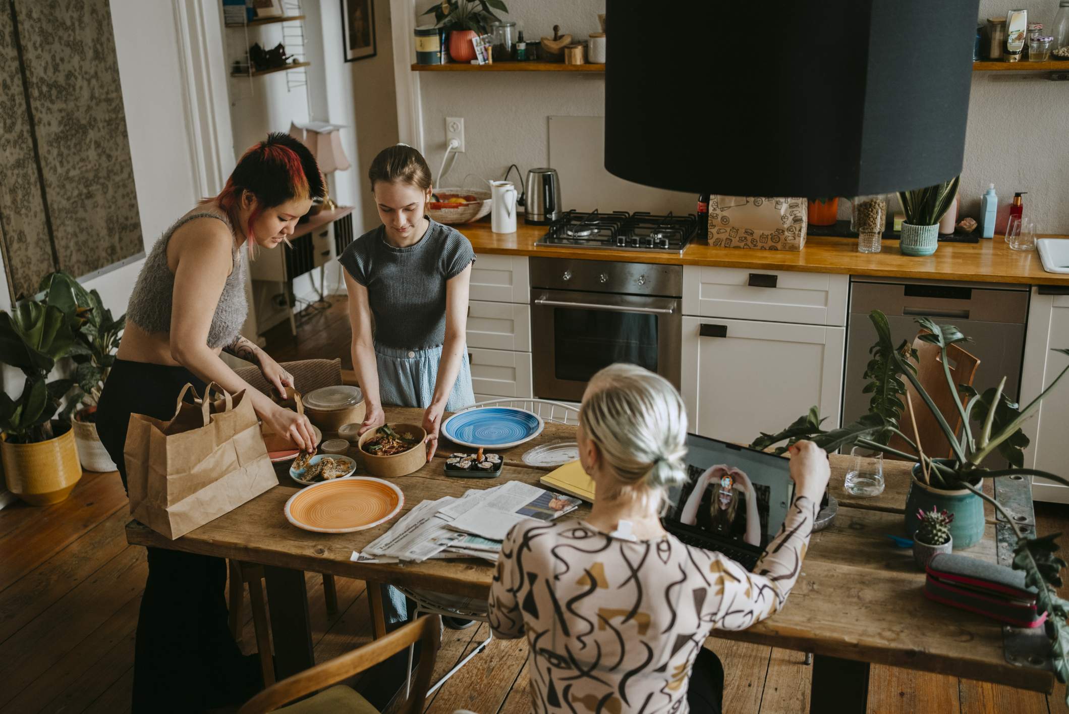 A group enjoys a restaurant meal in their home kitchen, thanks to a third-party delivery platform.
