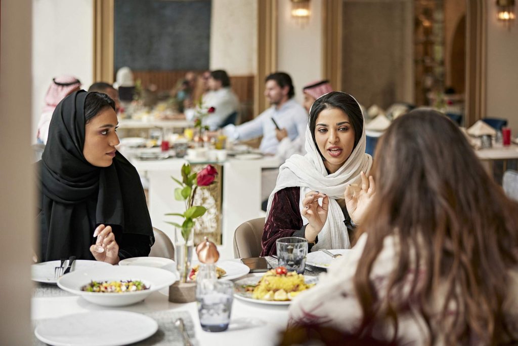 Image depicts a group of people dining at a restaurant. 