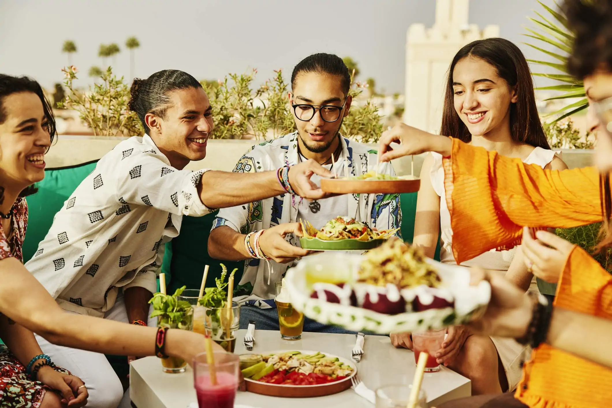 Image depicts a group of diners sharing a plate of food at a restaurant.