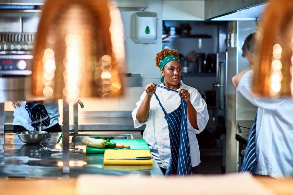 Image depicts two restaurant workers having a conversation in the kitchen.