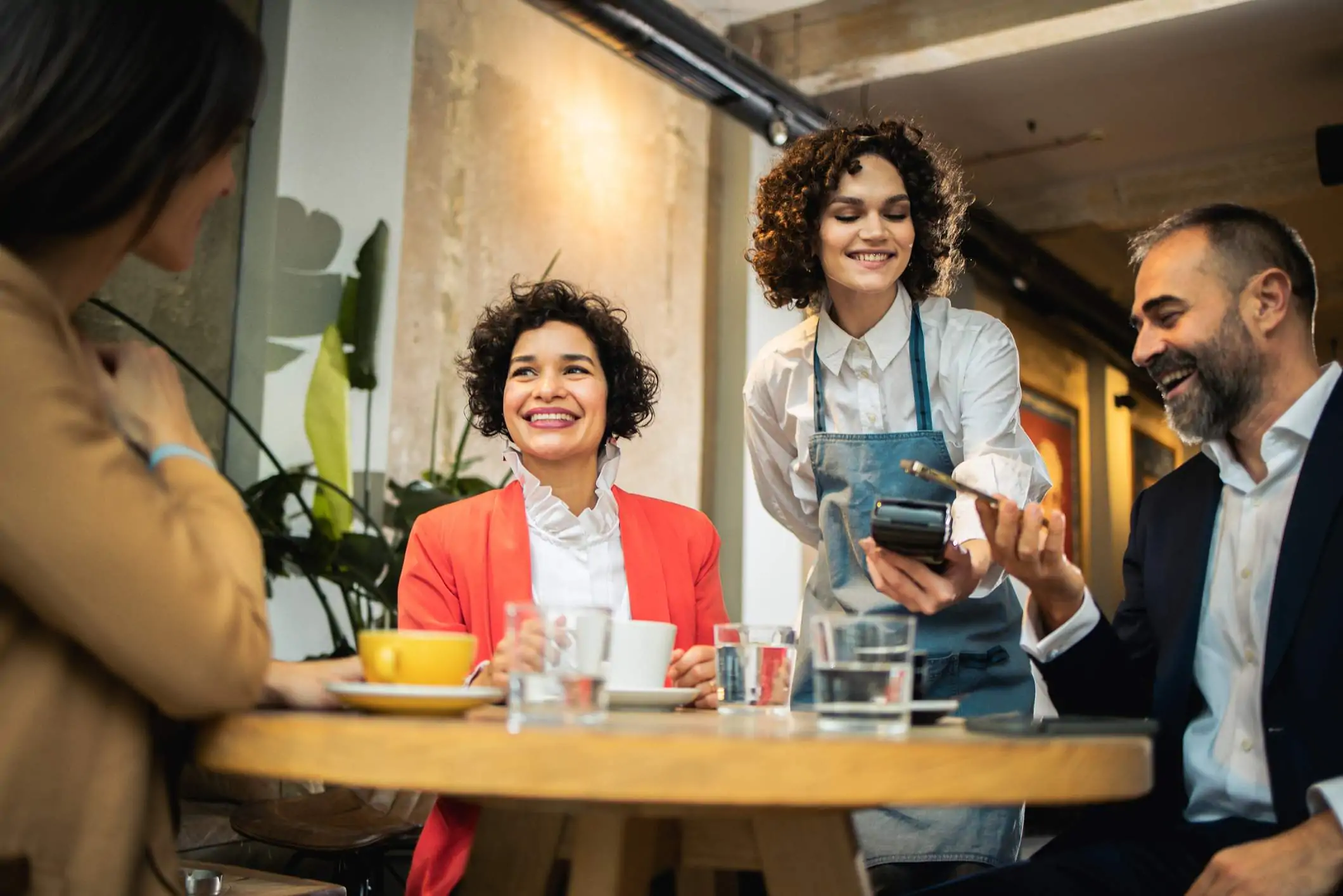 Image depicts a server taking payment from a guest.