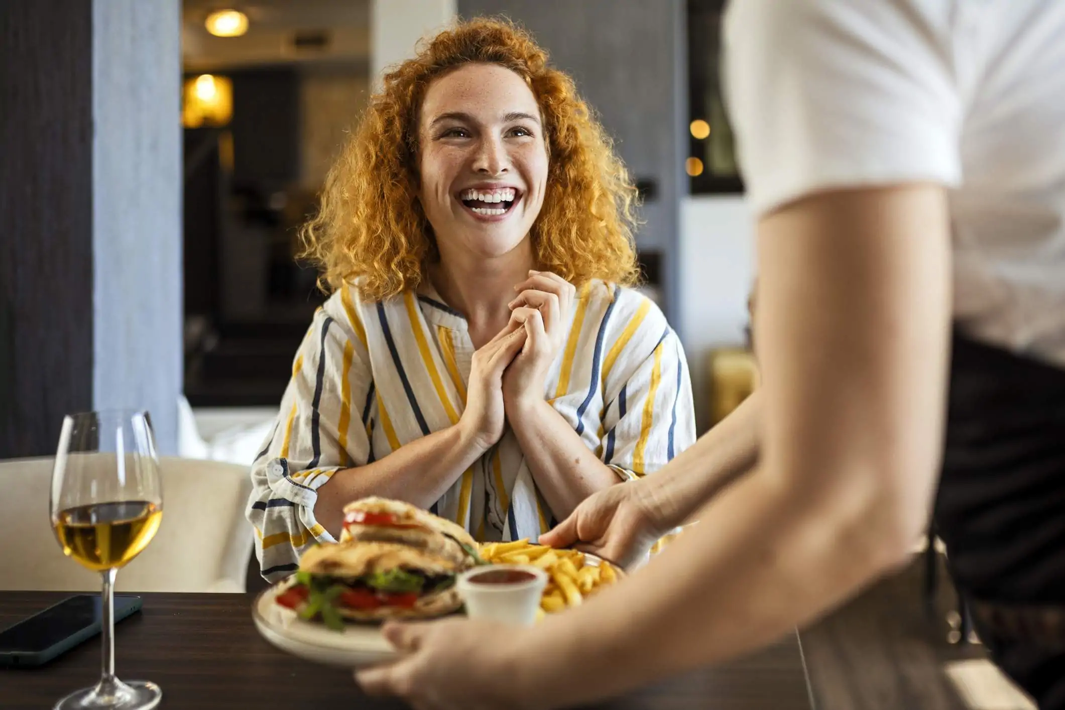 Loyalty rewards programs in action: A server puts a full plate down before a happy and excited guest