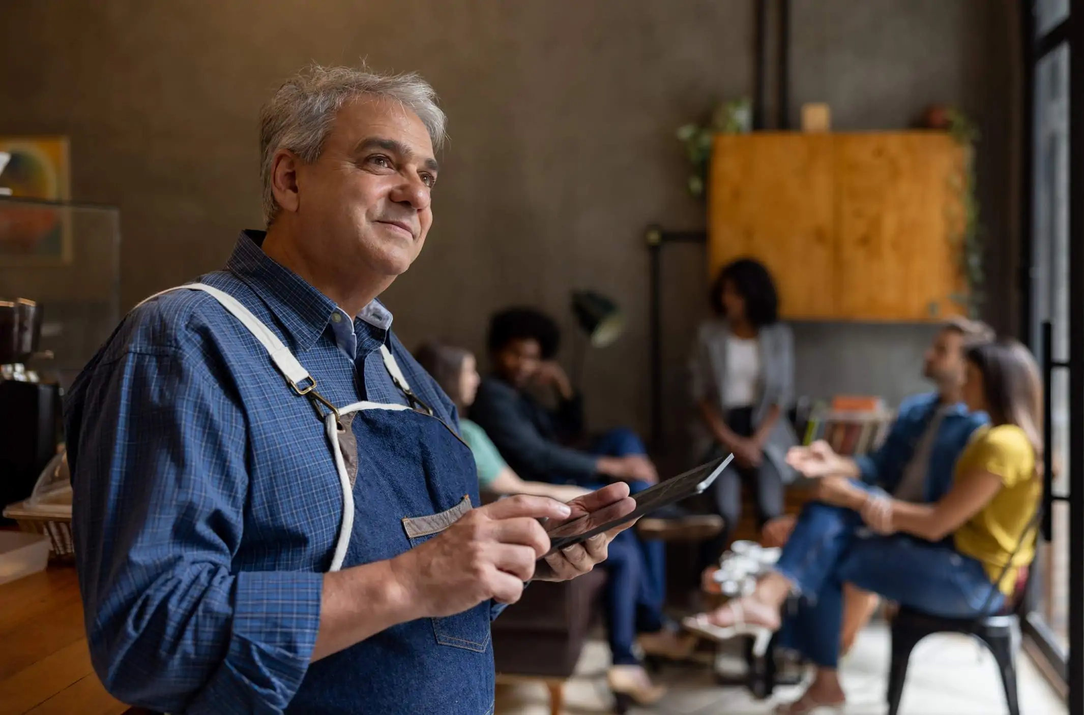 Image depicts a restaurant worker holding a tablet.